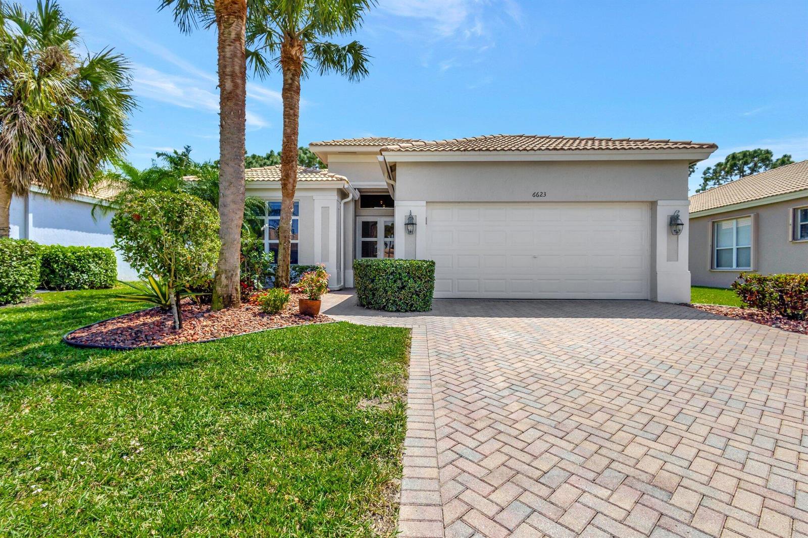 A single-story house with a beige stucco exterior, a two-car garage, and a paved driveway — 6623 Southport Drive, Boynton Beach FL 33472, BOYNTON BEACH, FL