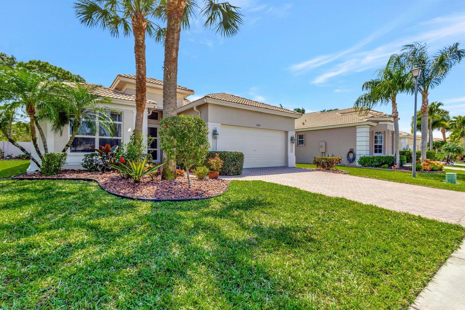 A single-story suburban house with a beige stucco exterior, tile roof, and paved driveway — 6623 Southport Drive, Boynton Beach FL 33472, BOYNTON BEACH, FL