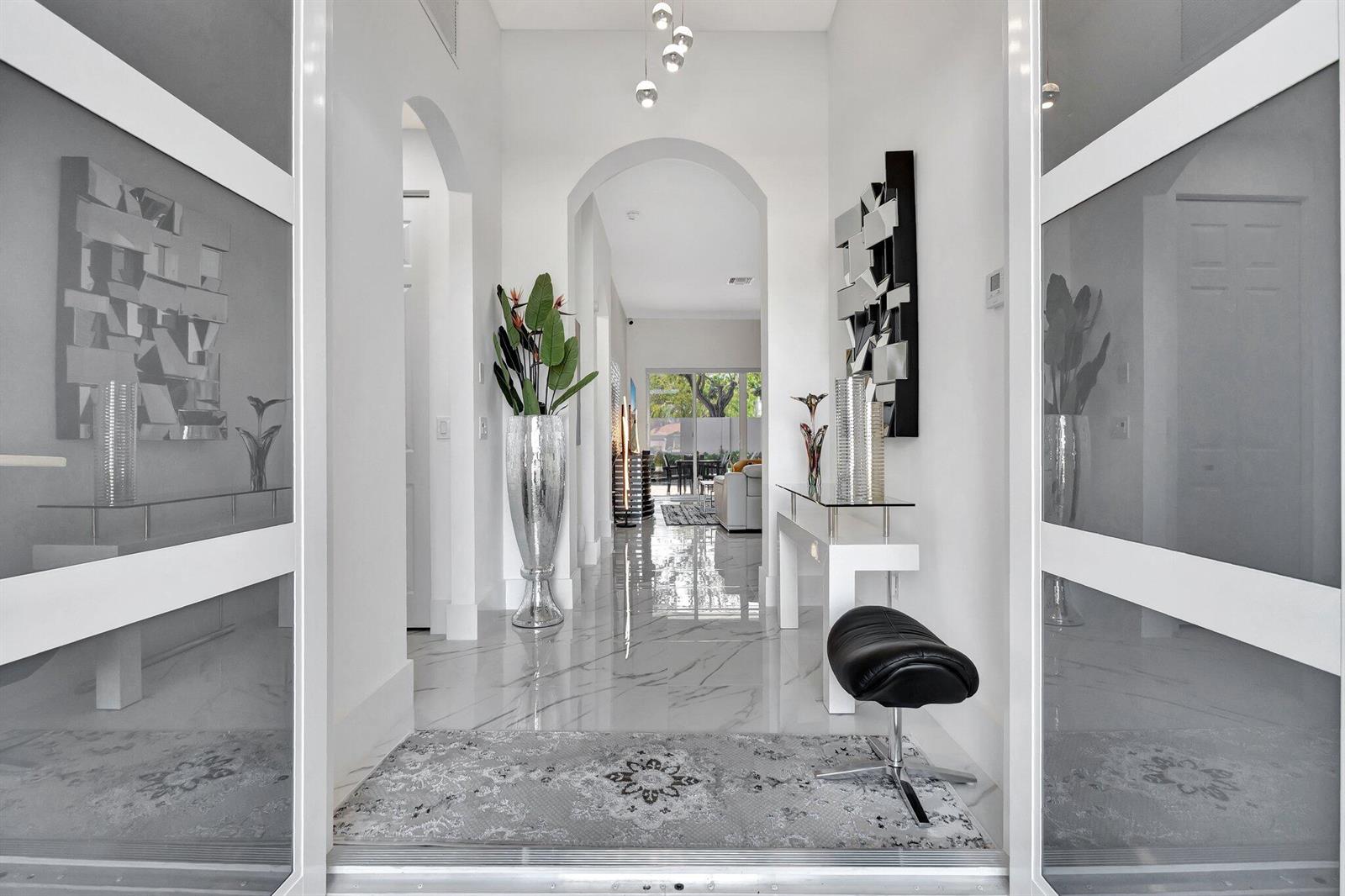 A bright, modern entryway features white walls, marble flooring, an arched hallway, and contemporary decor — 6623 Southport Drive, Boynton Beach FL 33472, BOYNTON BEACH, FL