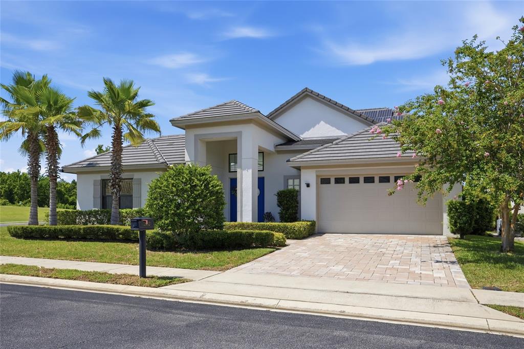 A single-story house with a paved driveway, two palm trees, and a two-car garage — 2562 HERITAGE GREEN AVENUE, DAVENPORT, FL
