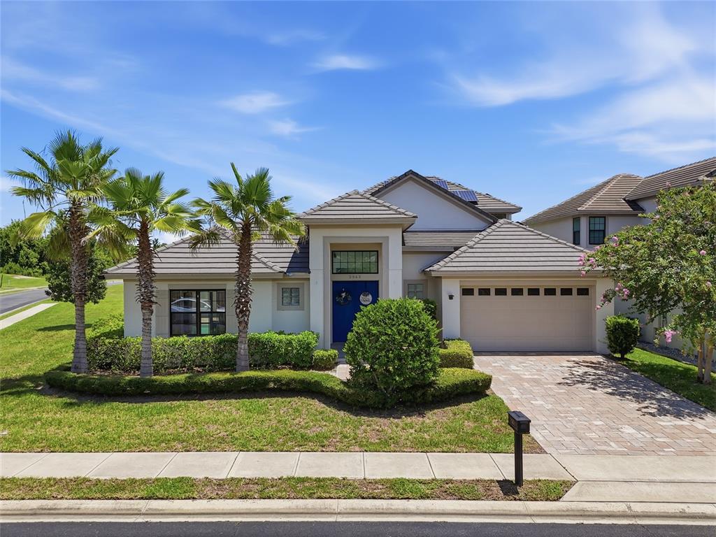 A single-story house with a tiled roof, blue front door, and a paved driveway — 2562 HERITAGE GREEN AVENUE, DAVENPORT, FL
