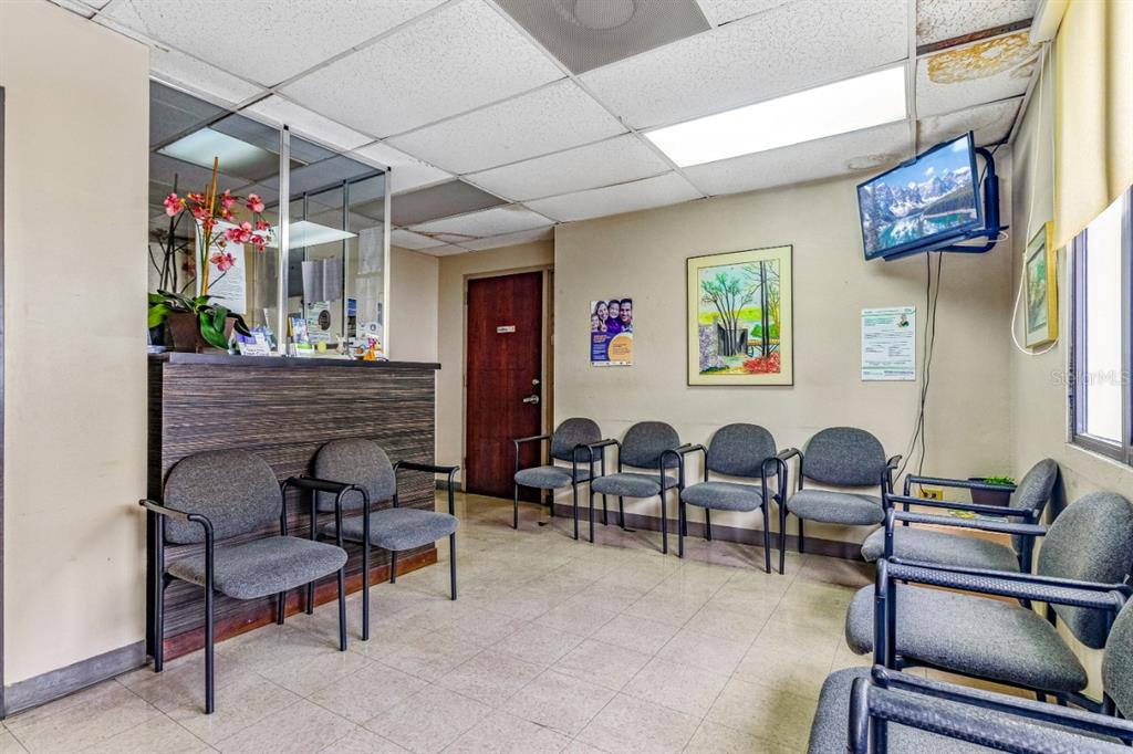 A waiting room features gray chairs, a reception desk, and a wall-mounted television — 506 EDIF. DR.ARTURO CADILLA, BAYAMON, PR
