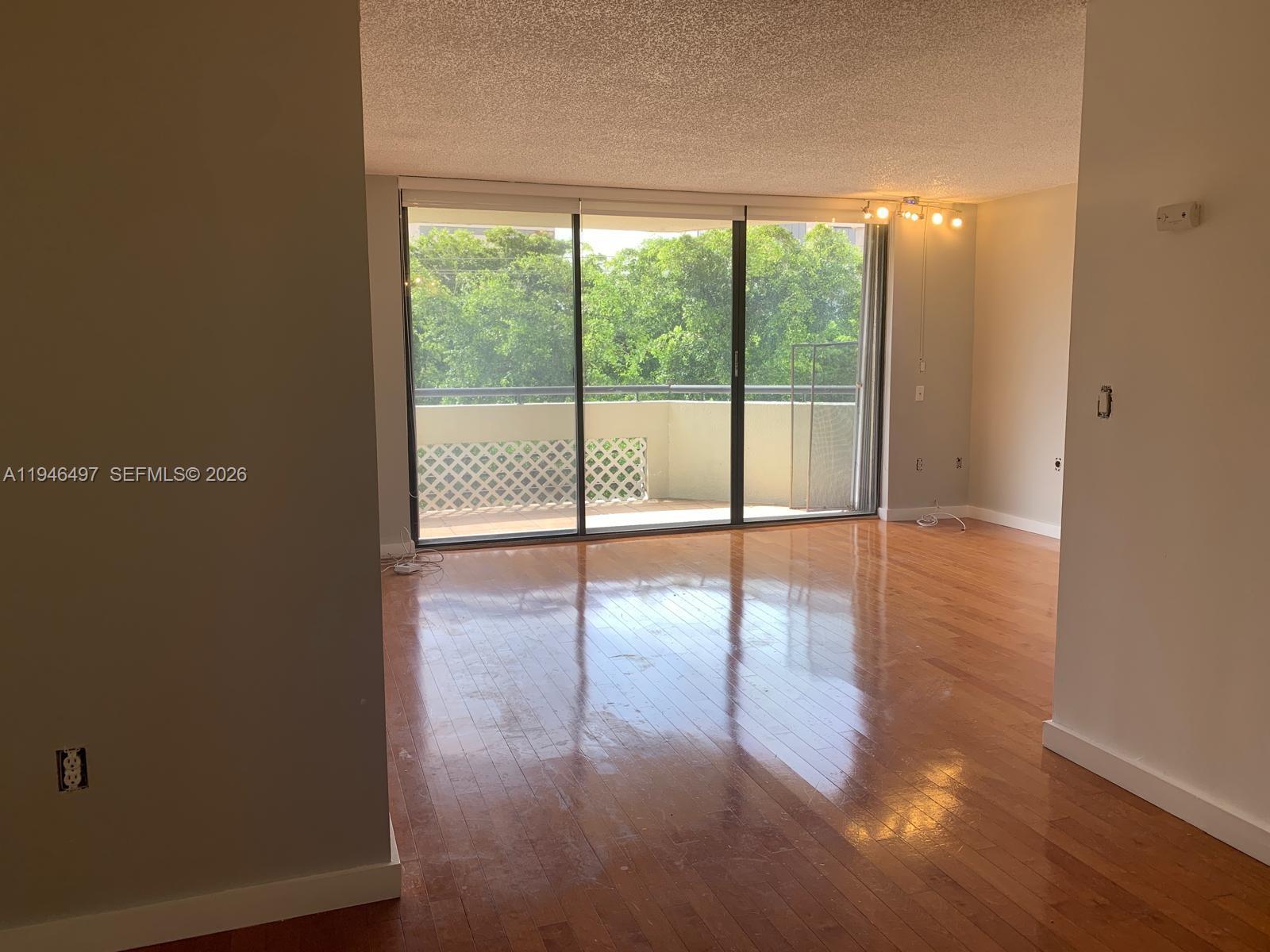 A living room features a grand piano, a gray sofa, a round coffee table, and television — 911 E Ponce De Leon Blvd # 403, Coral Gables FL 33134, CORAL GABLES, FL