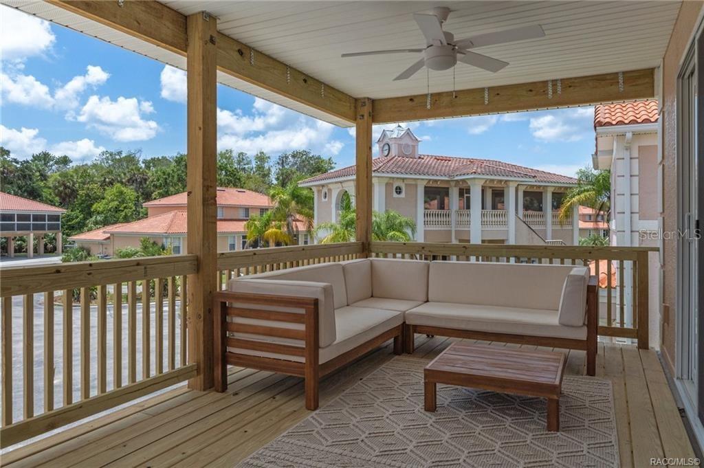 A covered wooden deck features a sectional sofa, a coffee table, and a ceiling fan — 4864 S AMSTEL DRIVE, HOMOSASSA, FL