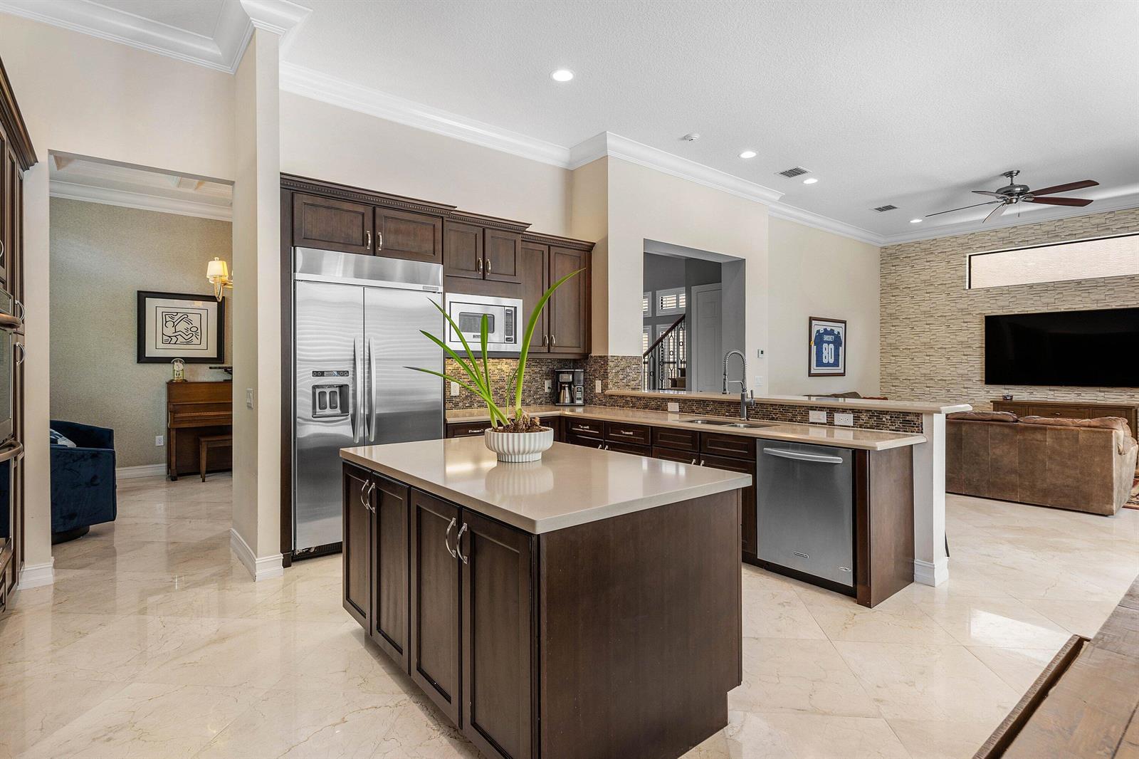 A kitchen with dark wood cabinets, a central island, and stainless steel appliances — 8658 Lewis River Road, Delray Beach FL 33446, DELRAY BEACH, FL