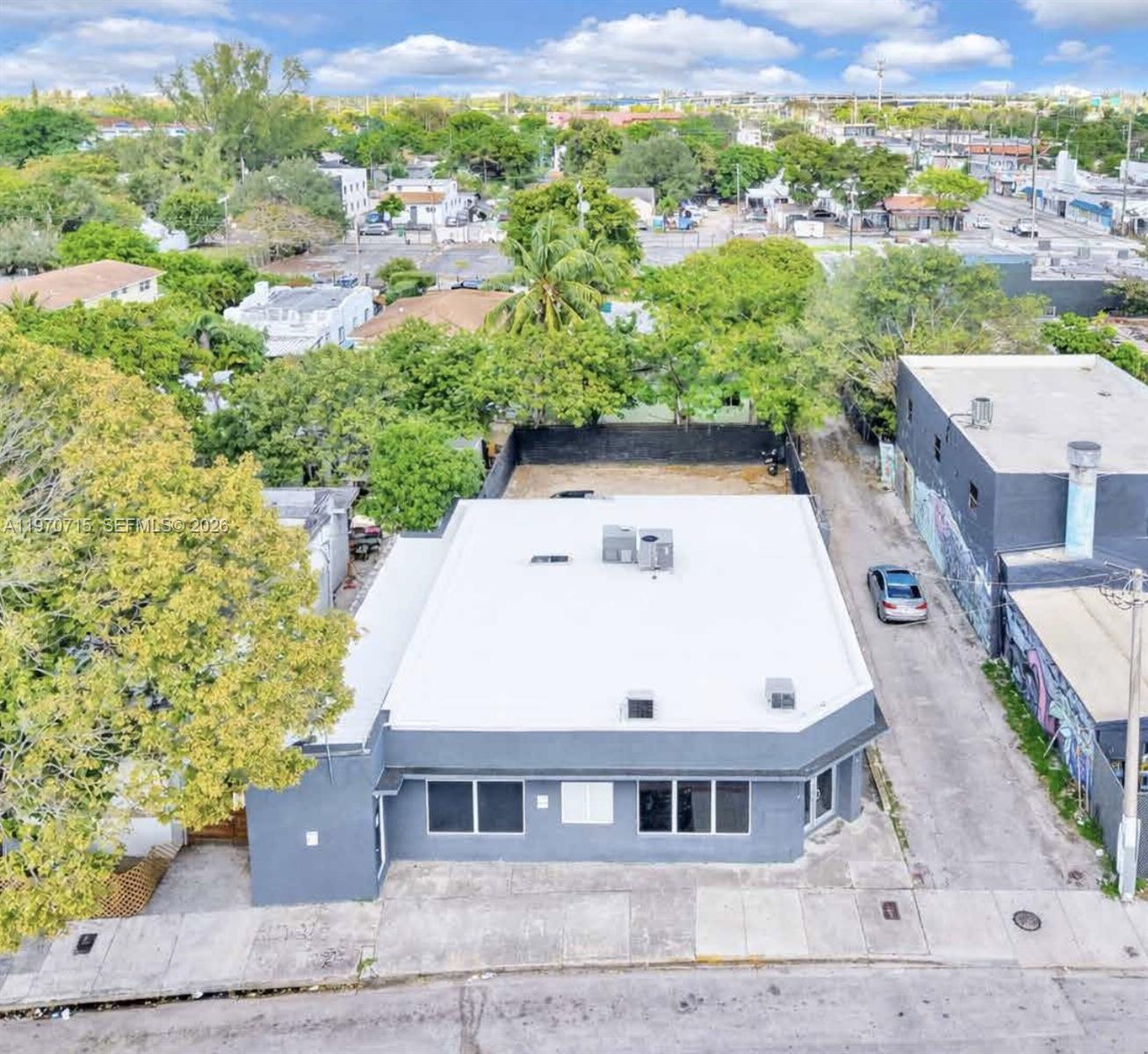 An aerial view shows a gray commercial building with a flat roof and adjacent lot — 719 NW 29th St, Miami FL 33127, MIAMI, FL