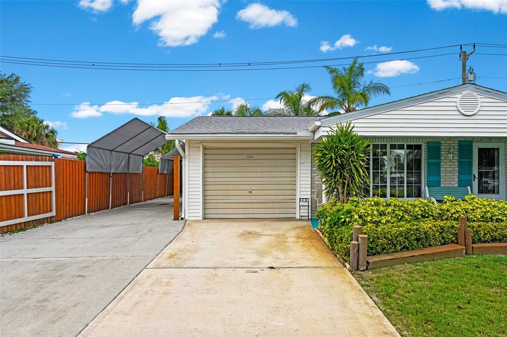 A single-story house features a beige garage door, a concrete driveway, and a wooden fence — 2545 EDNOR STREET, PORT CHARLOTTE, FL