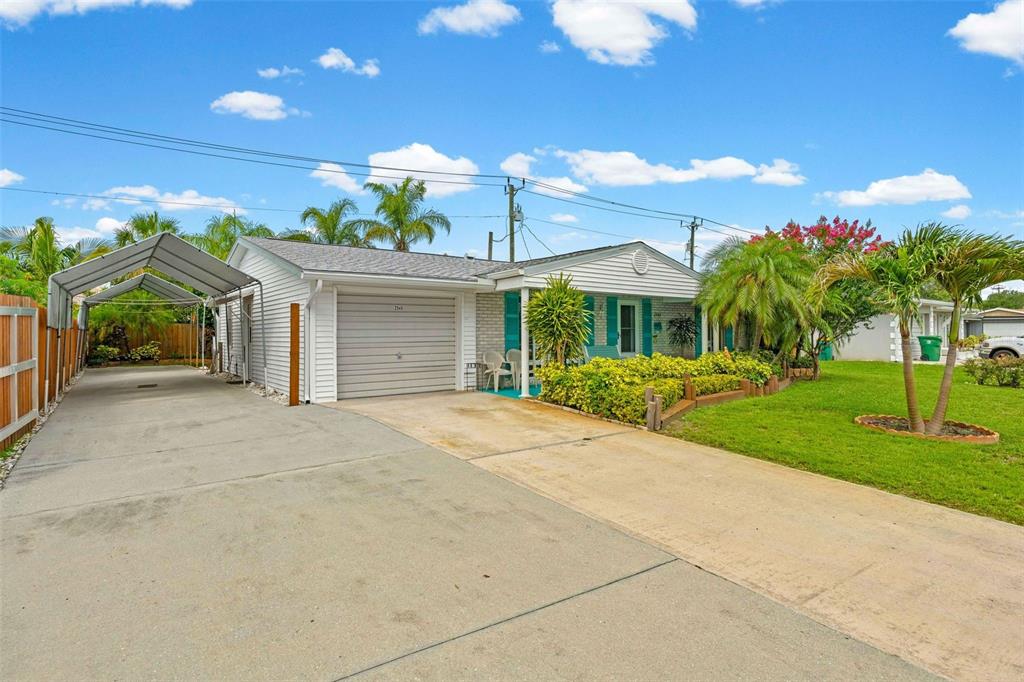 A single-story house features a concrete driveway, a metal carport, and a front lawn — 2545 EDNOR STREET, PORT CHARLOTTE, FL