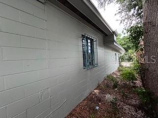 A side view of a light-colored concrete block house with a window featuring security bars — 4219 5TH AVENUE N, ST PETERSBURG, FL