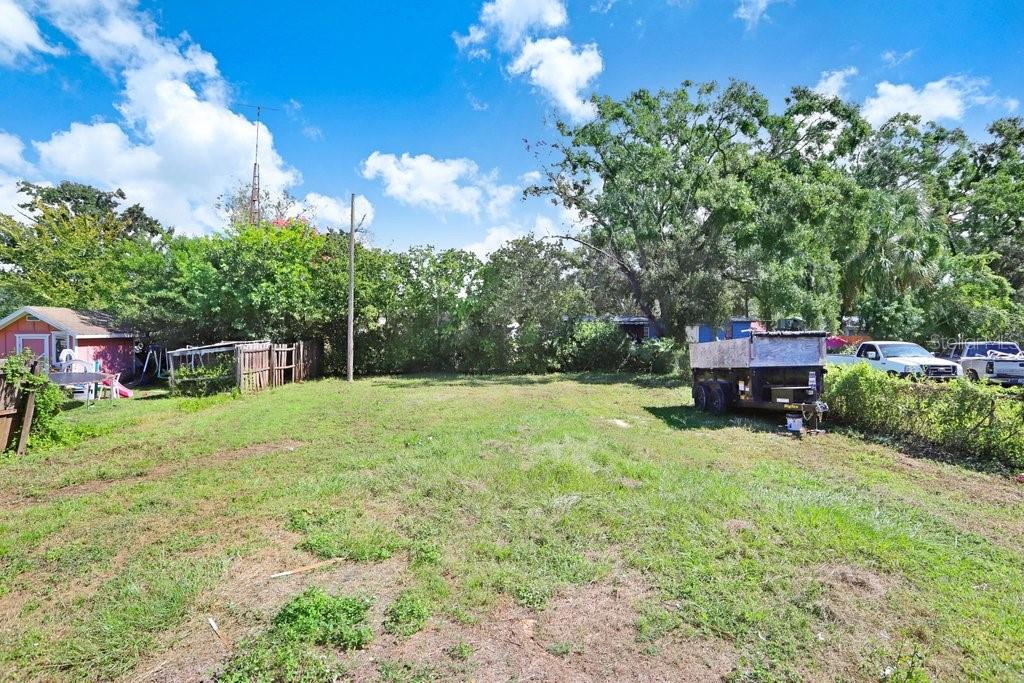 A grassy, vacant lot is enclosed by trees and a fence with a trailer parked nearby — 10414 RICHARDSON STREET, GIBSONTON, FL