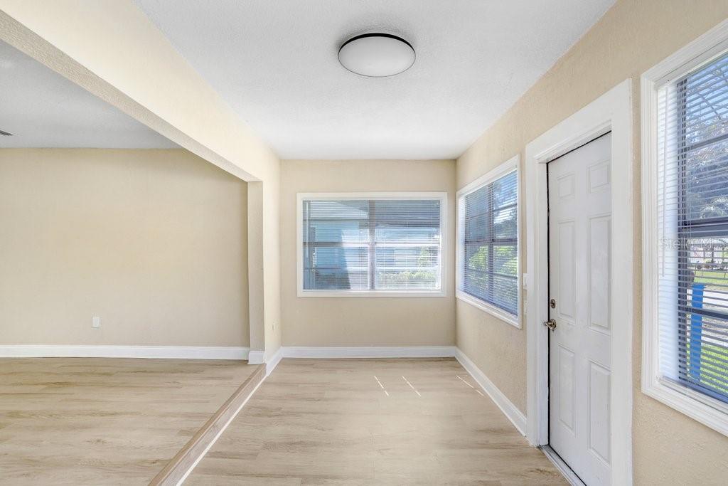 A bright room with light wood-look flooring, beige walls, a ceiling light, and white trim — 10414 RICHARDSON STREET, GIBSONTON, FL
