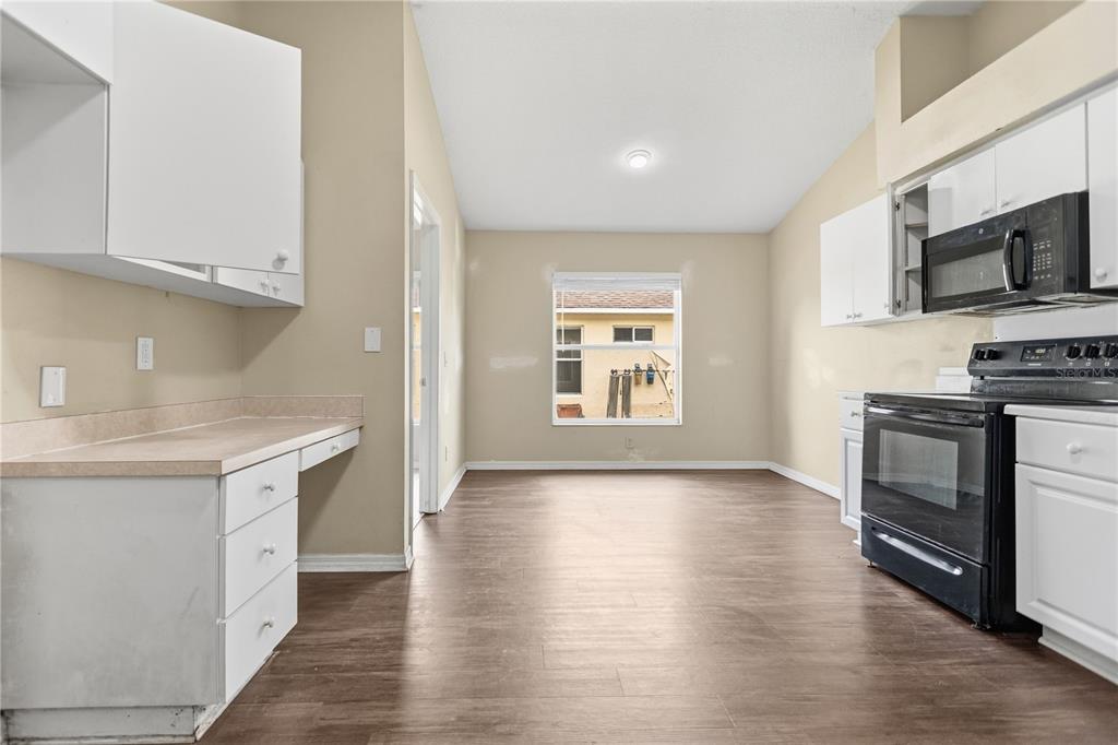 A kitchen with white cabinets, a black oven, and light-colored countertops on wood-look flooring — 1422 LAKE SHORE RANCH DRIVE, SEFFNER, FL