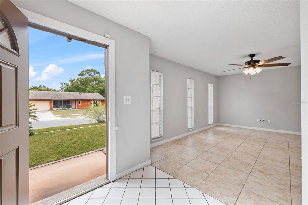An entryway with white tile floors opens into a living area with beige tile flooring — 4035 WENDY DRIVE, ORLANDO, FL