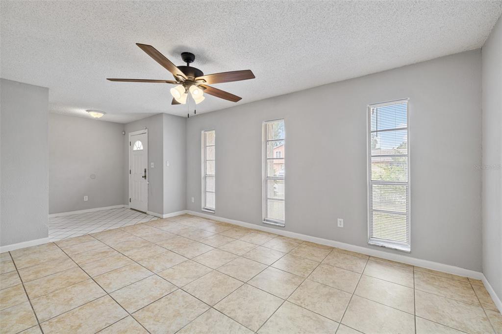 A living room with light gray walls, tile flooring, a ceiling fan, and three windows — 4035 WENDY DRIVE, ORLANDO, FL