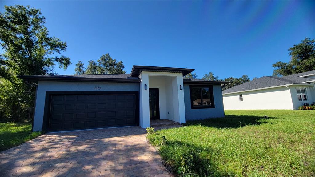 A single-story house with a gray exterior, a two-car garage, and a paved driveway — 3403 LANGMAID AVENUE, NORTH PORT, FL