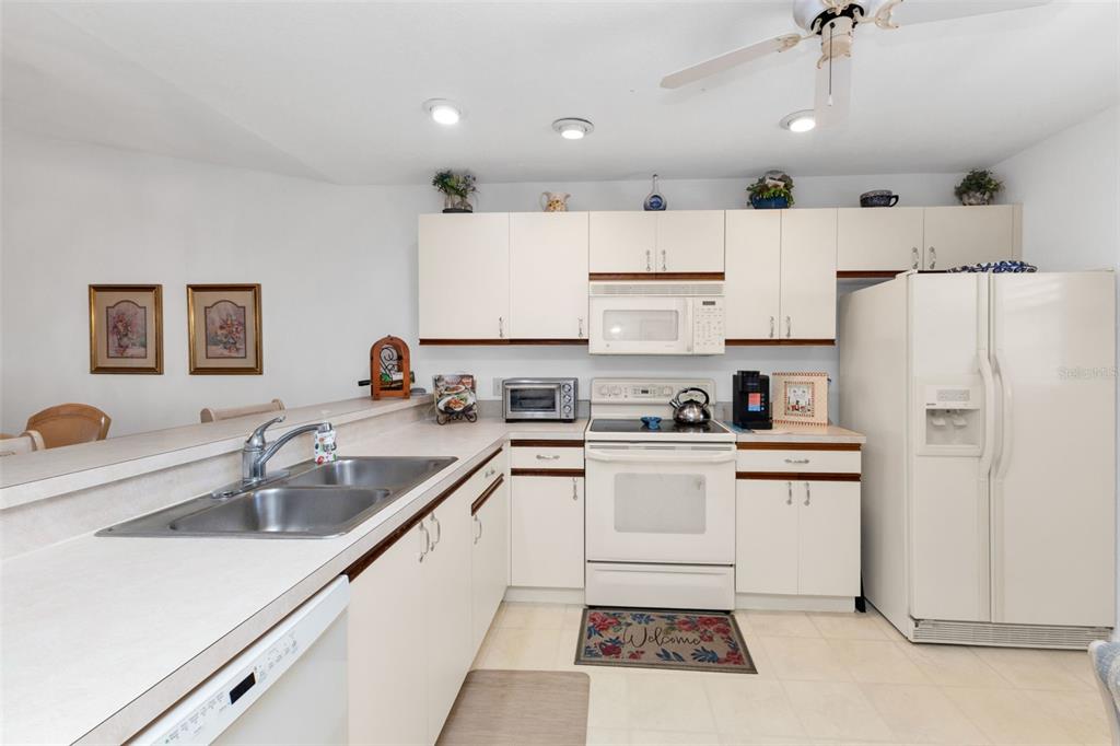 A kitchen features white cabinets, white appliances, a double sink, and a tiled floor — 175 KINGS HIGHWAY UNIT 1032, PUNTA GORDA, FL