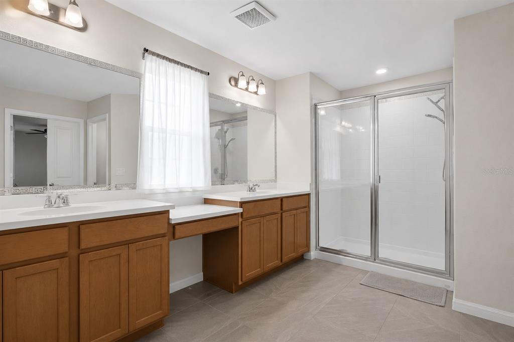 A bathroom with a double vanity, wood cabinets, a window, and a glass-enclosed shower — 1761 PETIOLE PLACE, KISSIMMEE, FL