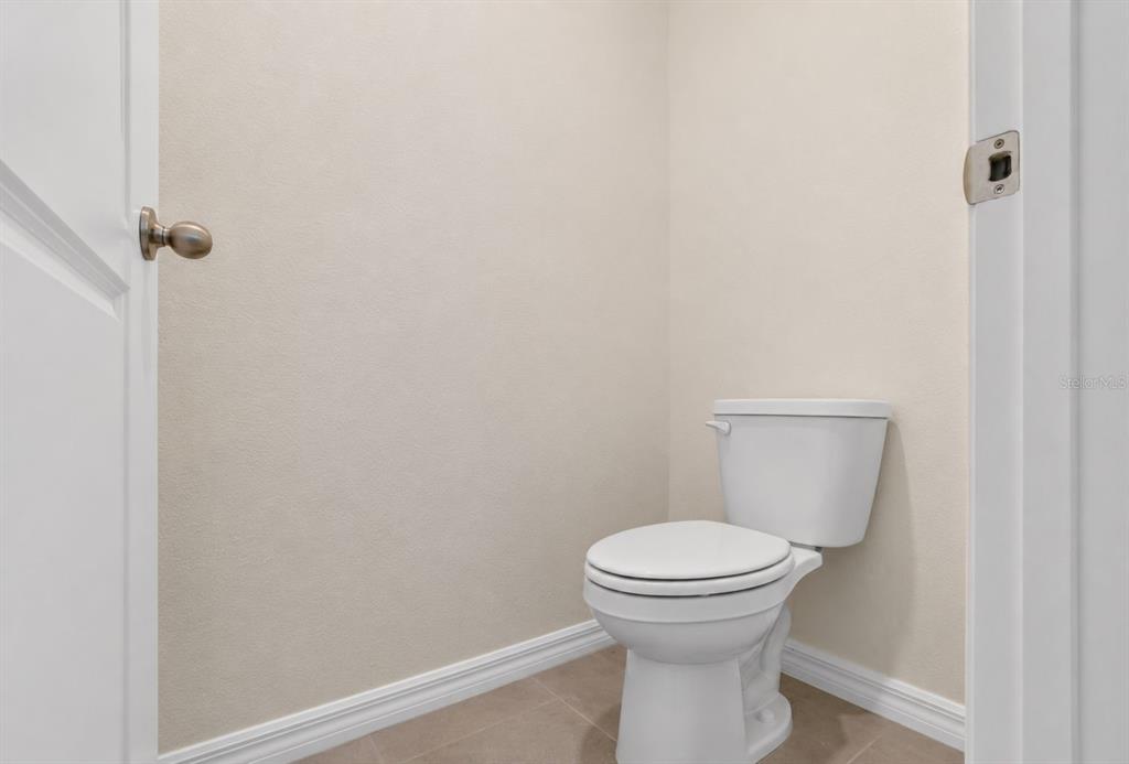 A small, neutral-toned water closet features a white toilet and light-colored tile flooring — 1761 PETIOLE PLACE, KISSIMMEE, FL