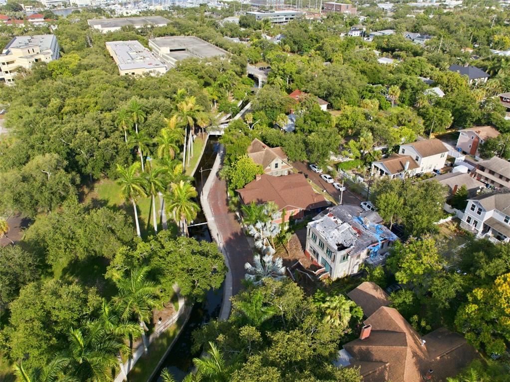 An aerial view shows a residential street with a canal, palm trees, and nearby buildings — 651 10TH AVE S, ST PETERSBURG, FL