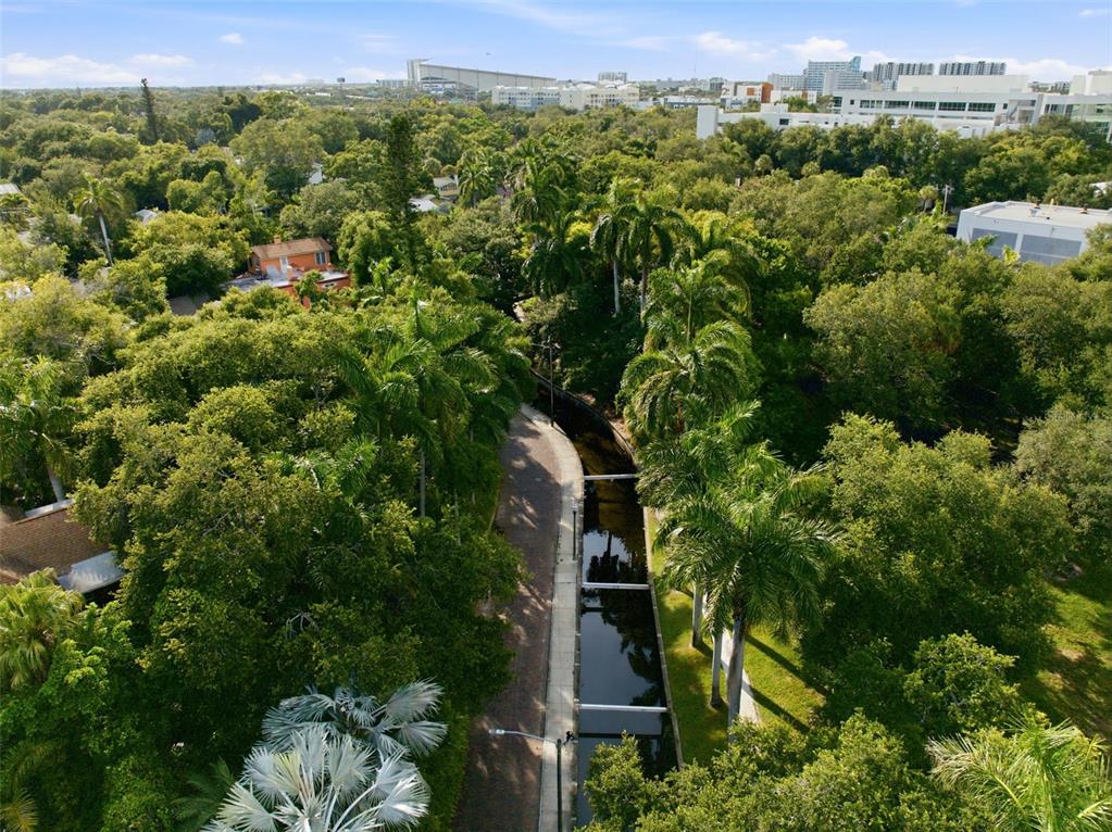 An aerial view shows a narrow canal bordered by a paved path and lush trees — 651 10TH AVE S, ST PETERSBURG, FL