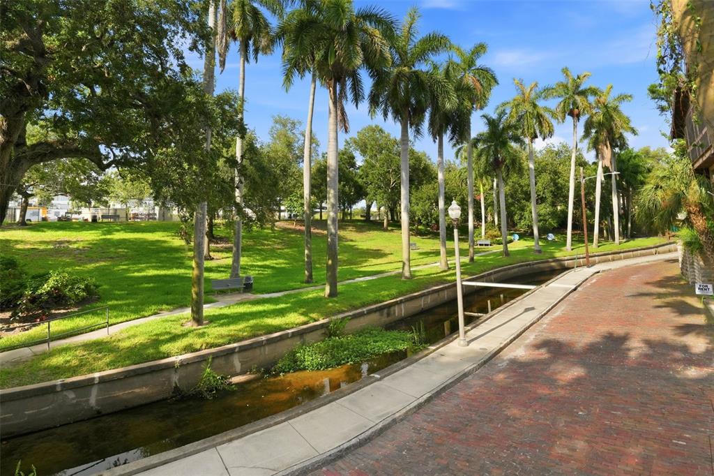 A brick path runs alongside a narrow canal next to a grassy park with palm trees — 651 10TH AVE S, ST PETERSBURG, FL