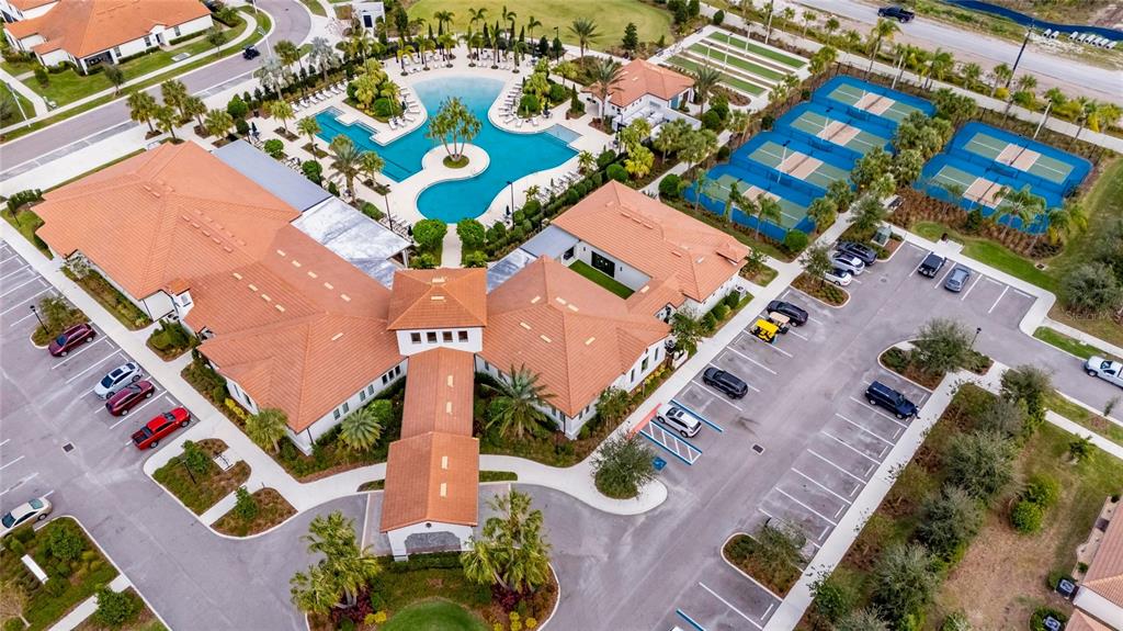 An aerial view shows a community clubhouse with a swimming pool and tennis courts — 17219 SCUBA CREST STREET, WIMAUMA, FL