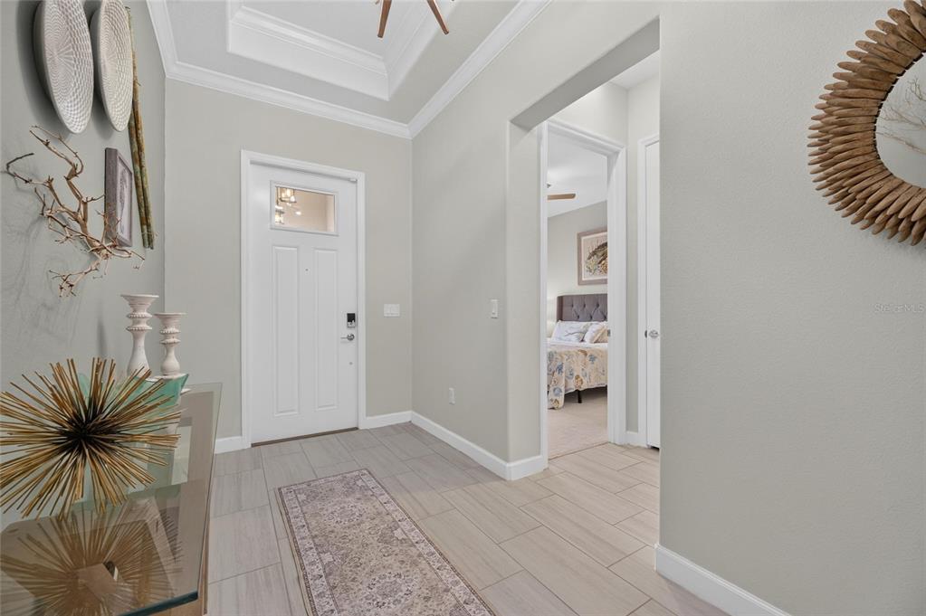 A bright entryway features light-colored tile flooring, a white front door, and a tray ceiling — 17219 SCUBA CREST STREET, WIMAUMA, FL
