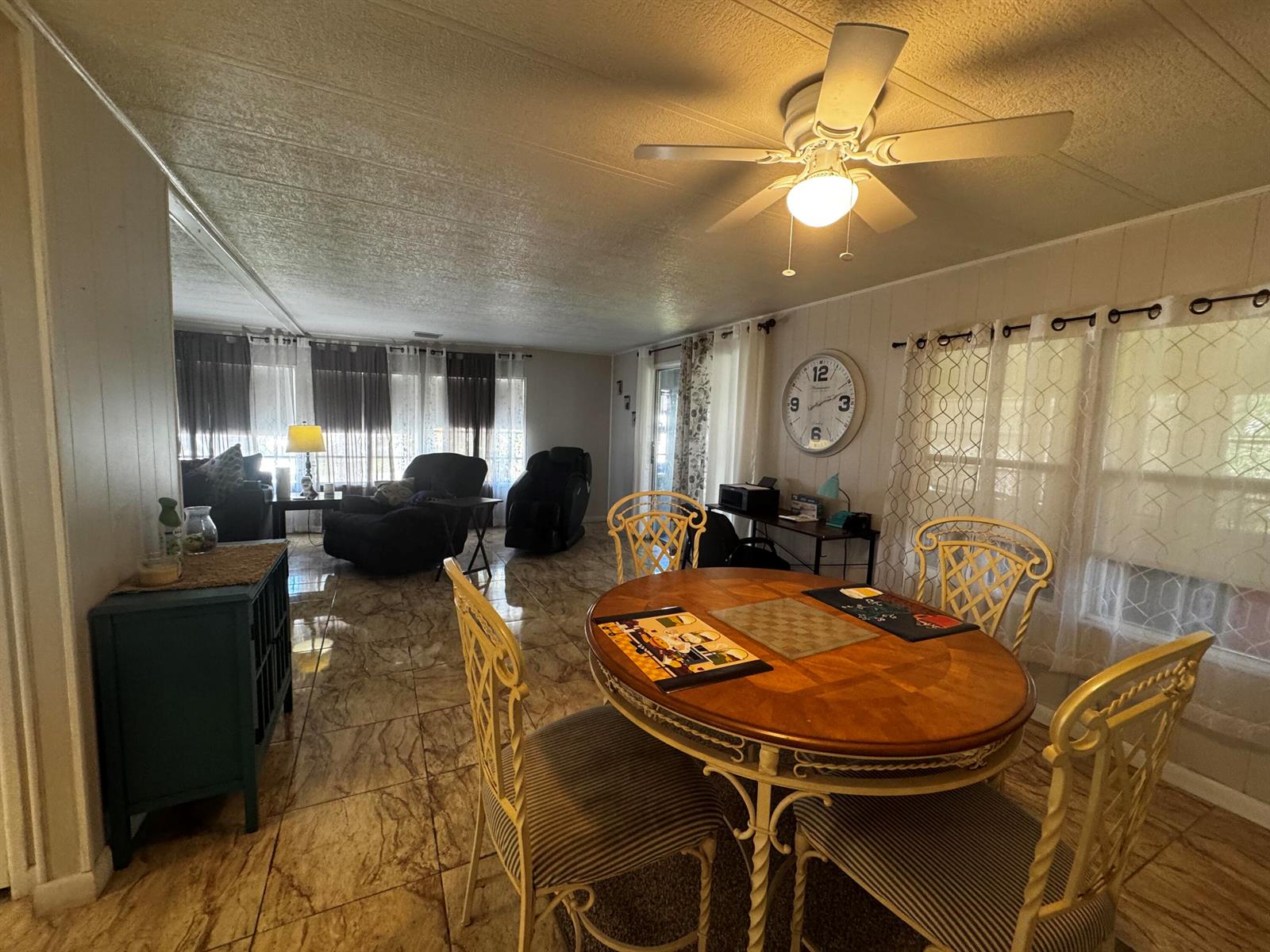 A dining area with a round wooden table sits adjacent to a living room with tile floors — 4242 3rd Court, Lantana FL 33462, LANTANA, FL