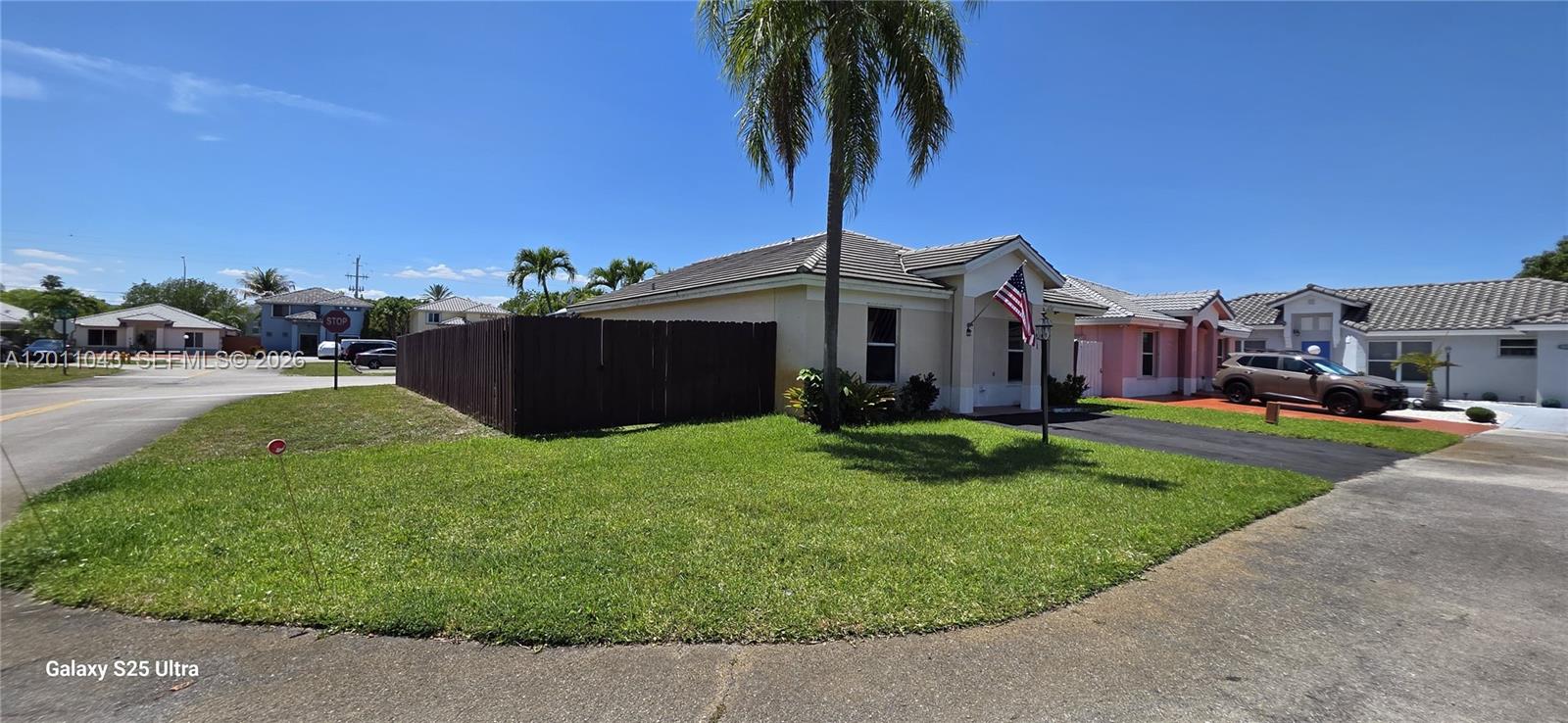 A single-story house with a brown fence, a palm tree, and a parked SUV — 18516 NW 56th Ave, Miami Gardens FL 33055, MIAMI GARDENS, FL