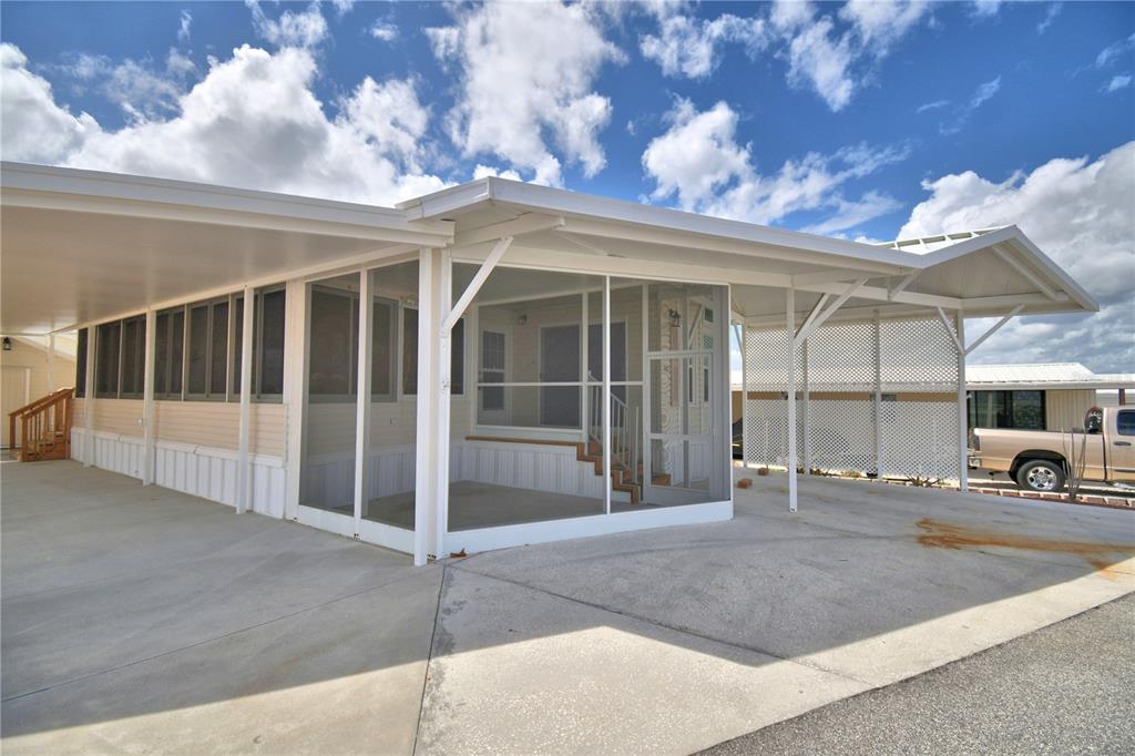 A mobile home exterior features a large screened-in porch and a spacious concrete carport — 251 PATTERSON ROAD UNIT B23, HAINES CITY, FL