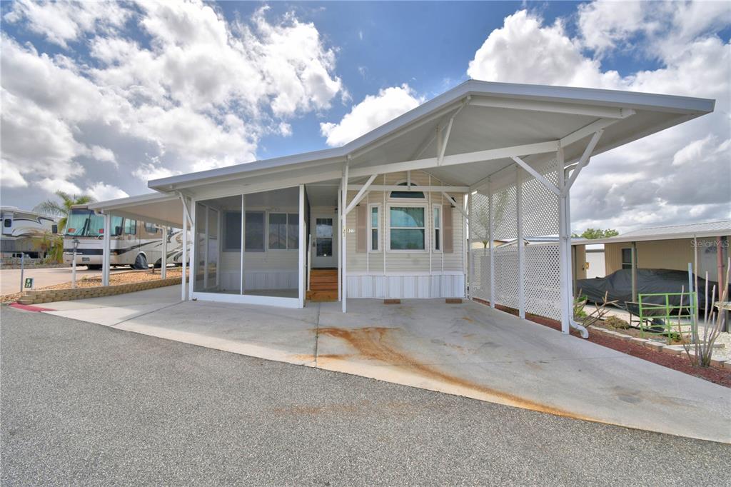 A manufactured home with a screened-in porch and a large attached carport — 251 PATTERSON ROAD UNIT B23, HAINES CITY, FL