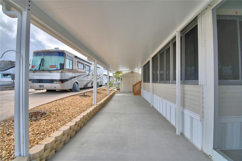 A covered concrete carport runs alongside a mobile home with a screened-in porch area — 251 PATTERSON ROAD UNIT B23, HAINES CITY, FL