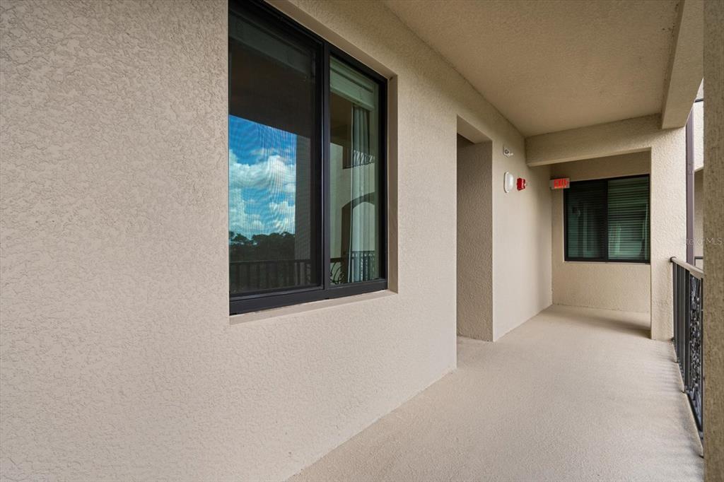 A covered outdoor balcony features beige stucco walls, a dark-framed window, and a metal railing — 17118 VARDON TERRACE UNIT 306, LAKEWOOD RANCH, FL