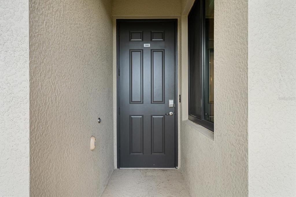 A dark-colored front door with the number 306 is set within a recessed stucco entryway — 17118 VARDON TERRACE UNIT 306, LAKEWOOD RANCH, FL