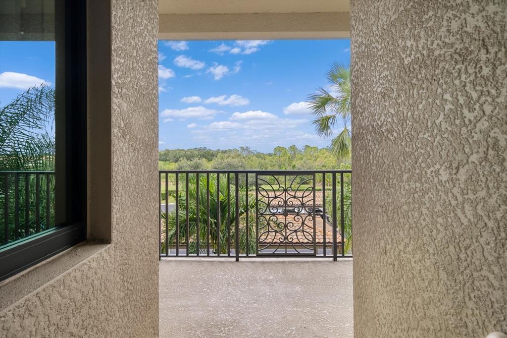A balcony with a decorative metal railing overlooks a view of trees and a blue sky — 17118 VARDON TERRACE UNIT 306, LAKEWOOD RANCH, FL