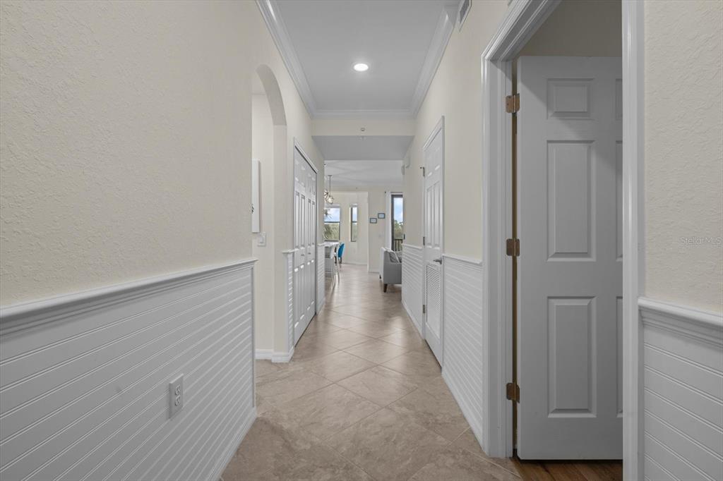 A hallway with white wainscoting and tile flooring leads toward an open living area — 17118 VARDON TERRACE UNIT 306, LAKEWOOD RANCH, FL