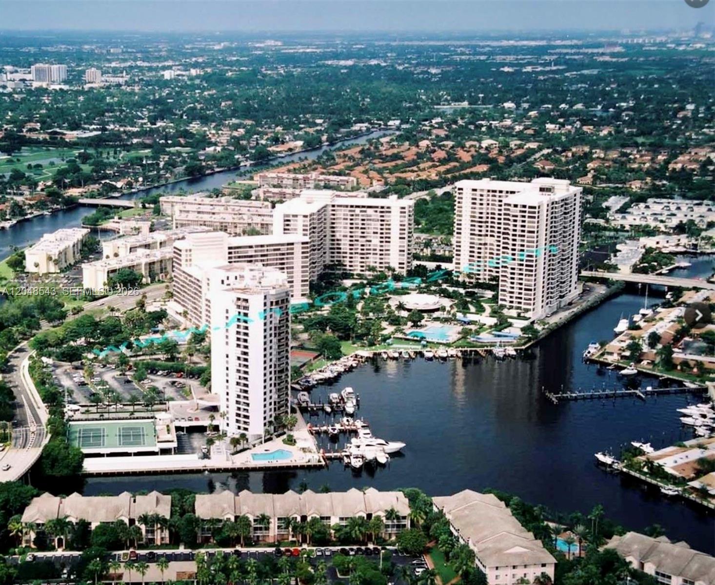 An aerial view of a waterfront condominium complex with a marina and swimming pools — 500 Three Islands Blvd # L25, Hallandale Beach FL 33009, HALLANDALE BEACH, FL