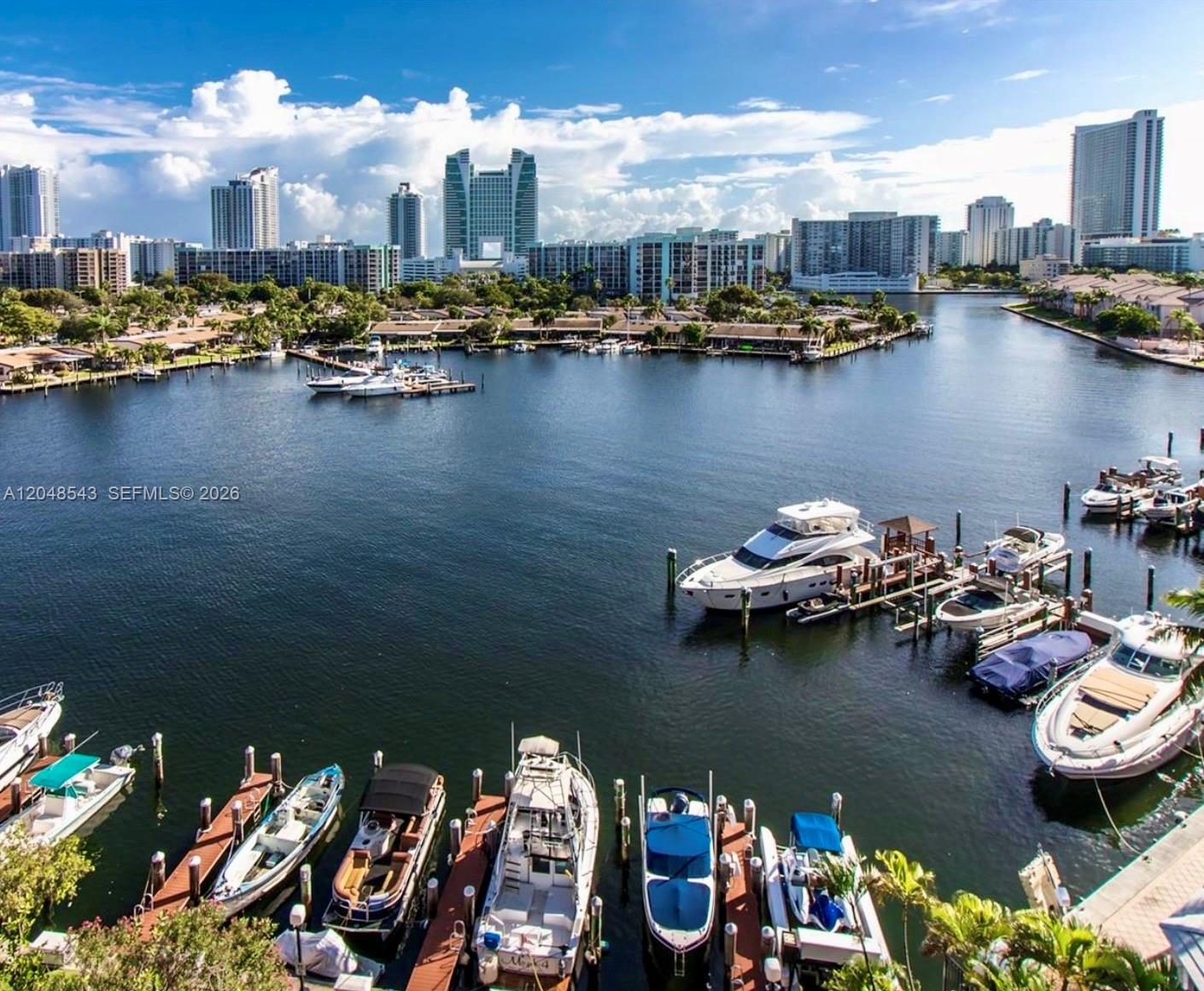 An elevated view of a marina with numerous docked boats and a city skyline background — 500 Three Islands Blvd # L25, Hallandale Beach FL 33009, HALLANDALE BEACH, FL