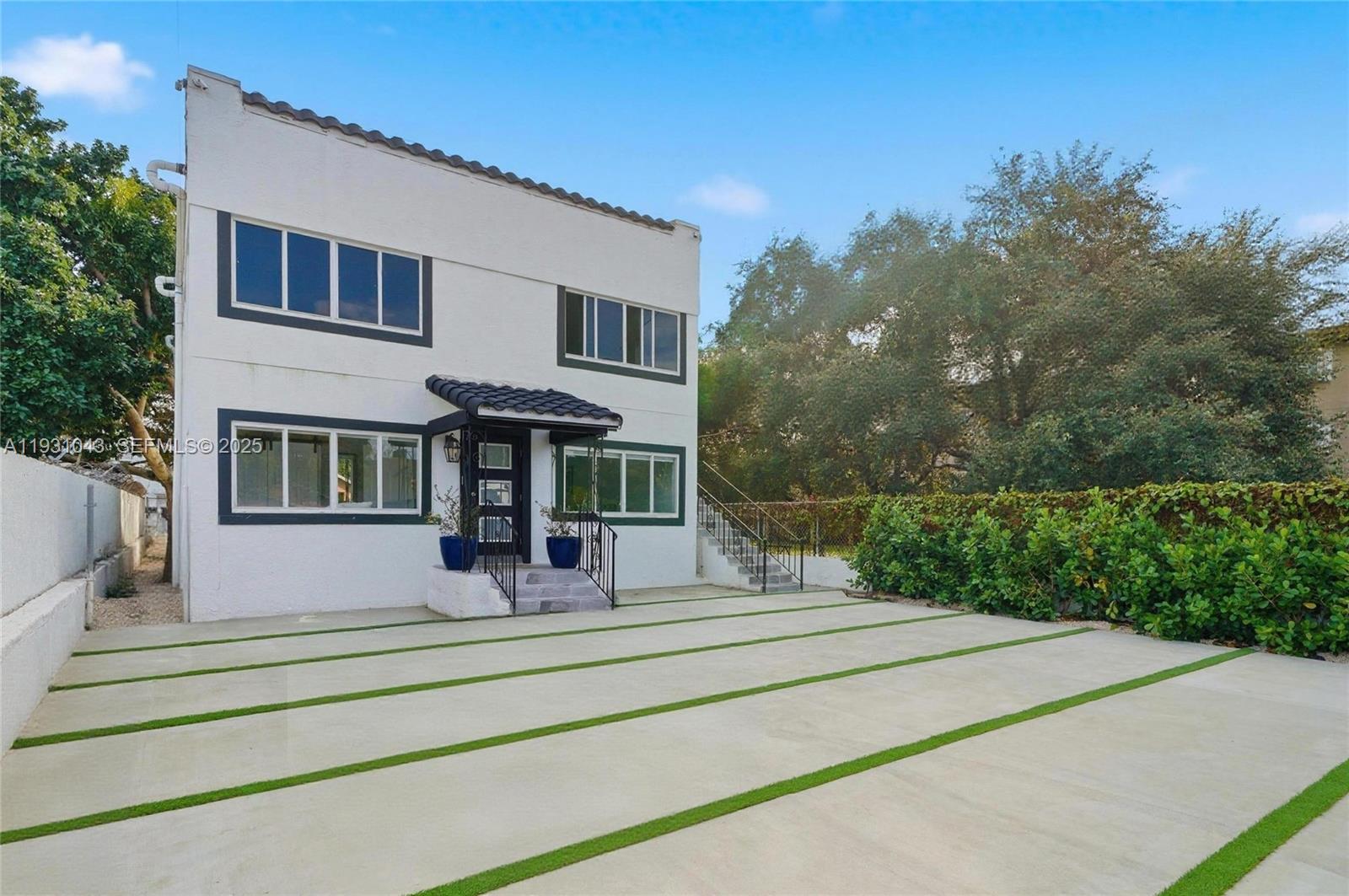 A two-story white house features a paved driveway with grass strips and a small porch — 1590 NW 38th St # 1, Miami FL 33142, MIAMI, FL
