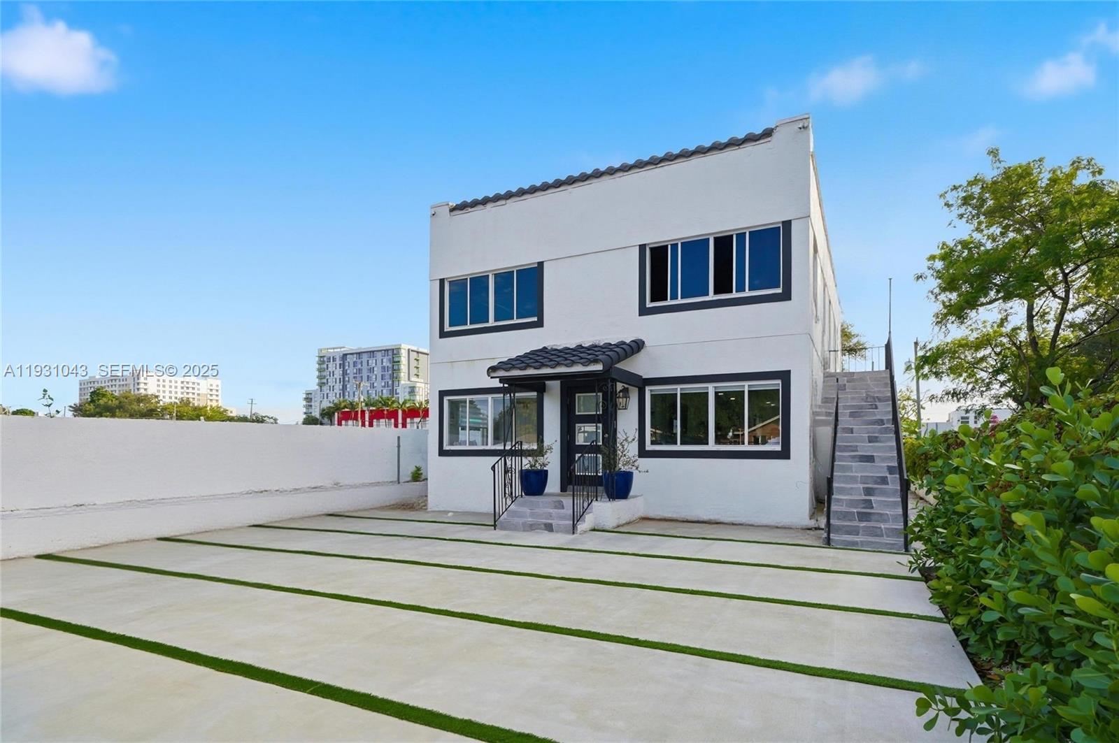 A two-story white building with black trim features an exterior staircase and paved driveway — 1590 NW 38th St # 1, Miami FL 33142, MIAMI, FL