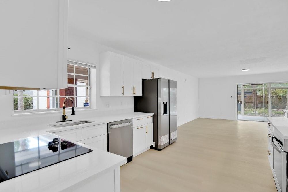 A modern kitchen with white cabinets, stainless steel appliances, and light wood flooring — 1241 MANCHESTER ROAD, MAITLAND, FL