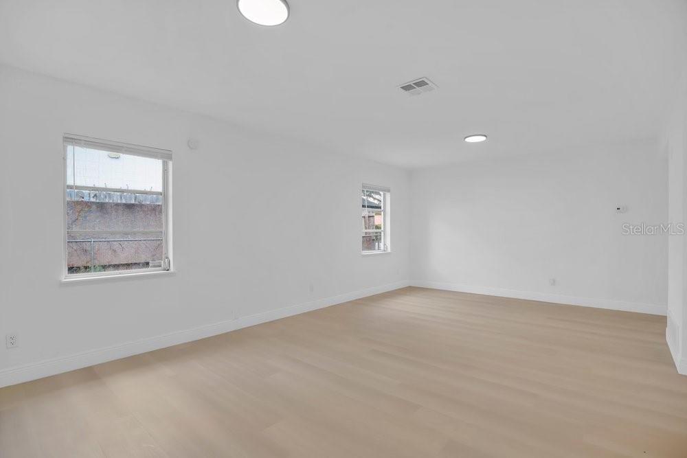 An empty room with white walls, light wood-look flooring, and two windows — 1241 MANCHESTER ROAD, MAITLAND, FL