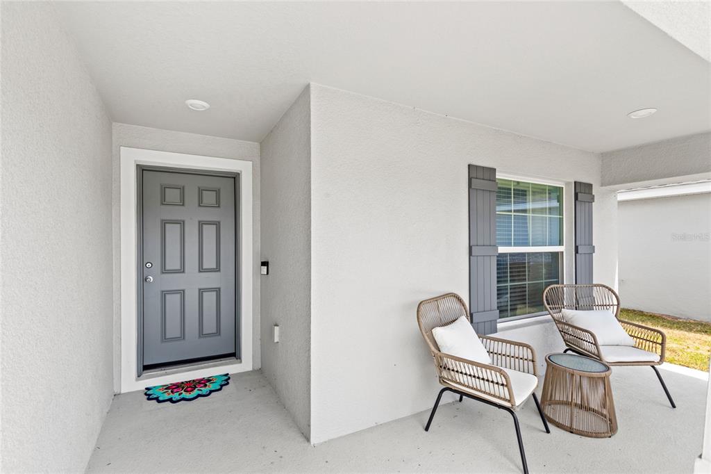 A covered front porch features a gray door, a window with shutters, and two chairs — 4215 SWAN STREET, HAINES CITY, FL