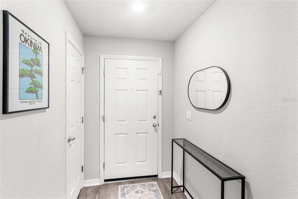 A bright entryway features a white front door, a console table, and framed wall art — 4215 SWAN STREET, HAINES CITY, FL