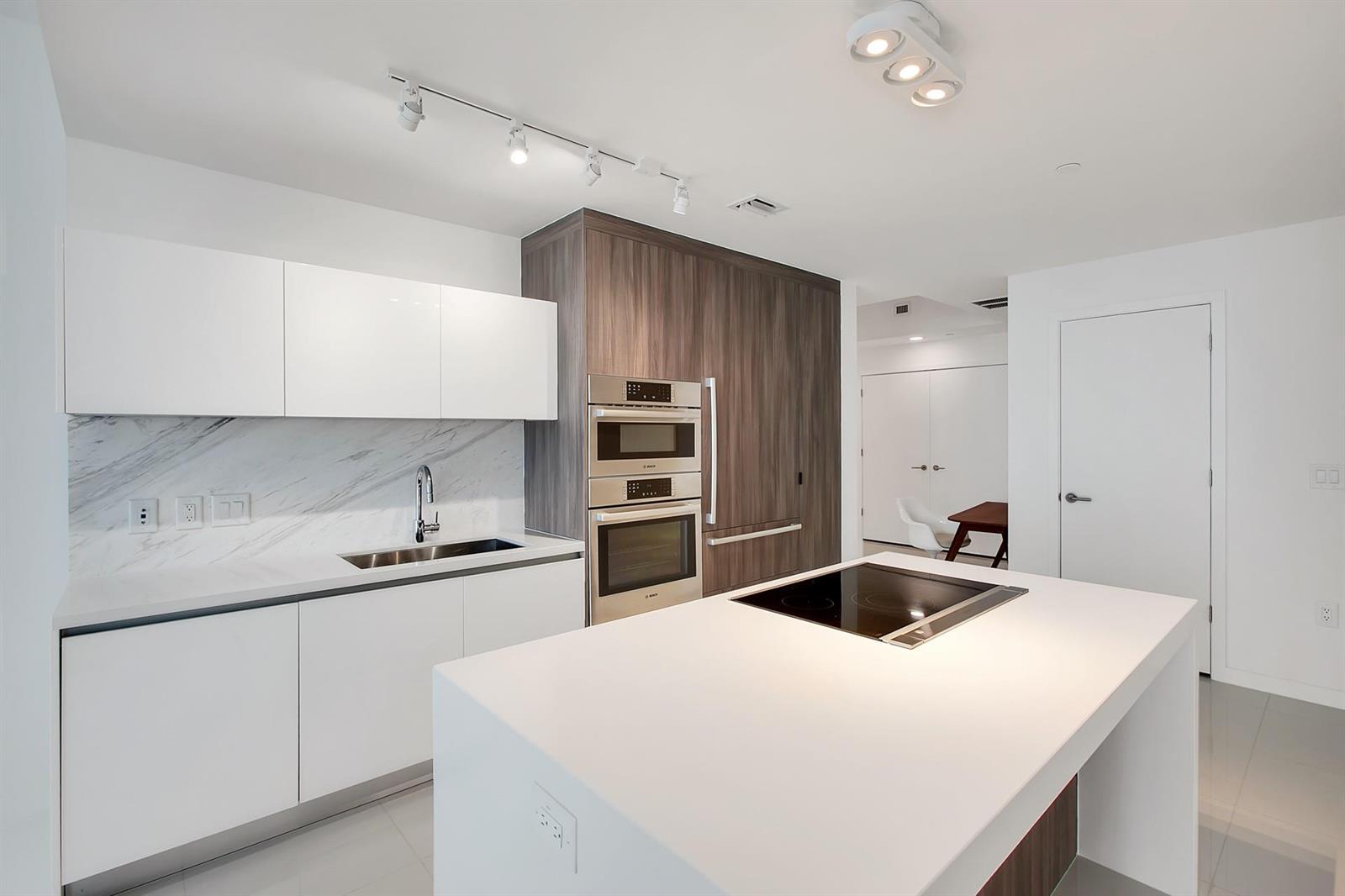 A modern kitchen features white cabinets, a marble backsplash, stainless steel appliances, and a central island — 851 NE 1st Avenue # 2005, Miami FL 33132, MIAMI, FL