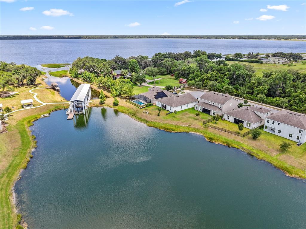 An aerial view shows houses near a pond and a large lake with a dock — 3385 WAUSEON DRIVE, ST CLOUD, FL