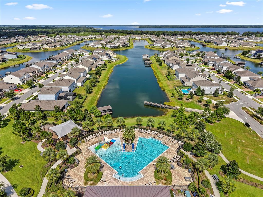 An aerial view shows a community pool and clubhouse surrounded by houses and a lake — 3385 WAUSEON DRIVE, ST CLOUD, FL