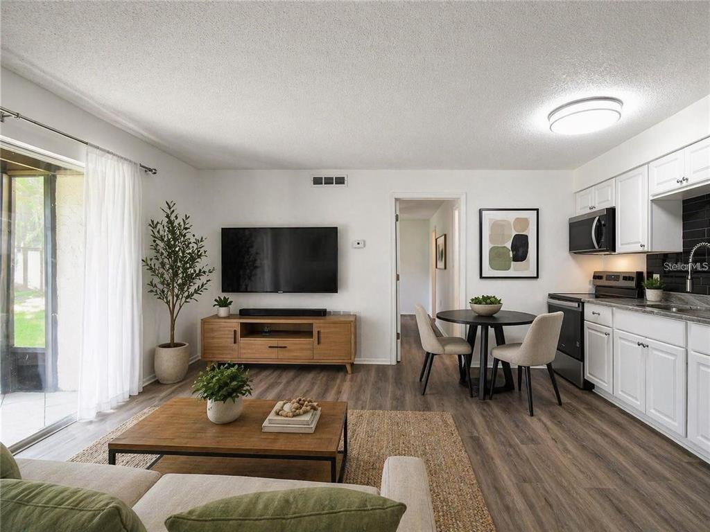 A living room and kitchen open-concept space with wood-look flooring and white cabinetry — 4215 E BAY DRIVE UNIT 1701B, CLEARWATER, FL