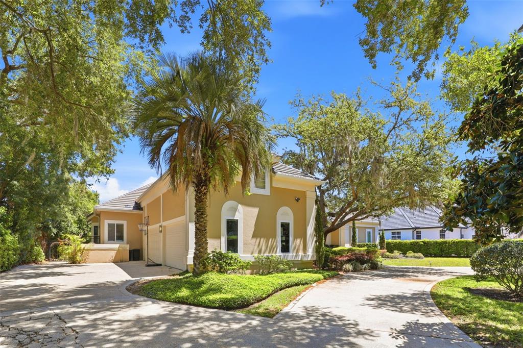 A tan house with a palm tree in the front yard and a paved driveway — 9151 POINT CYPRESS DRIVE, ORLANDO, FL