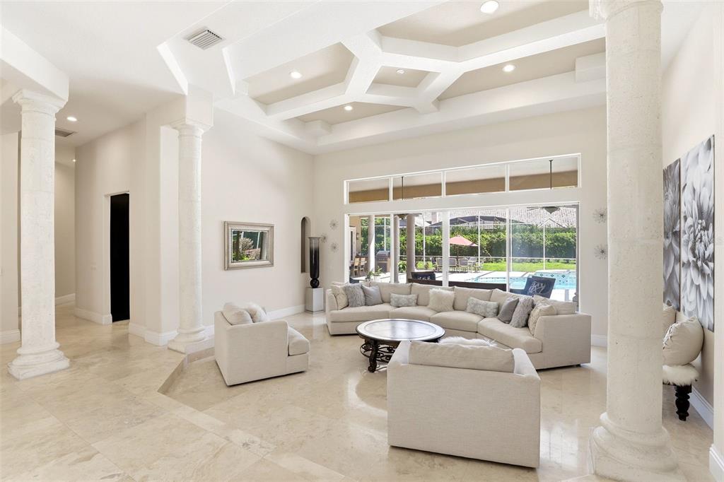 A spacious living room features stone columns, a coffered ceiling, and a large sectional sofa — 9151 POINT CYPRESS DRIVE, ORLANDO, FL